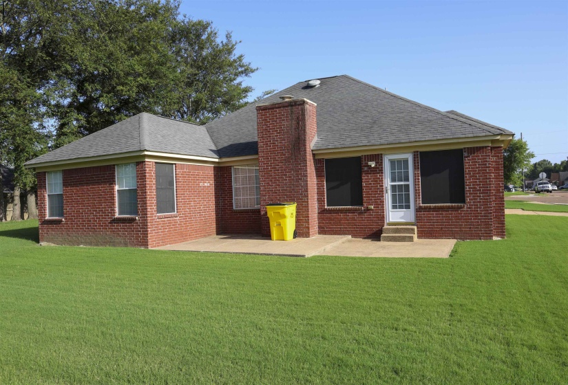 Brick exterior featuring a gabled roofline, a rear patio, and a chimney