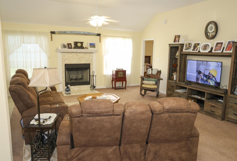 Living area featuring vaulted ceilings, a ceiling fan, and carpeted flooring