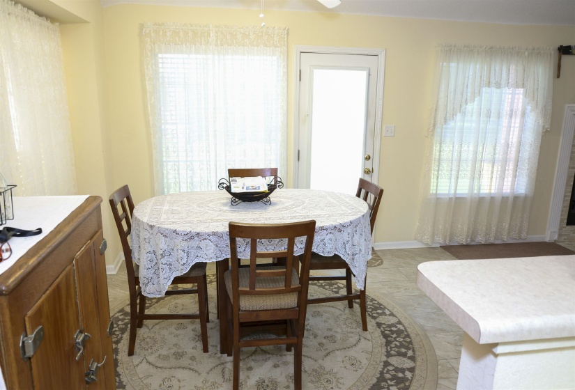Bright dining area featuring a glass-paned exterior door, multiple windows, and tile flooring