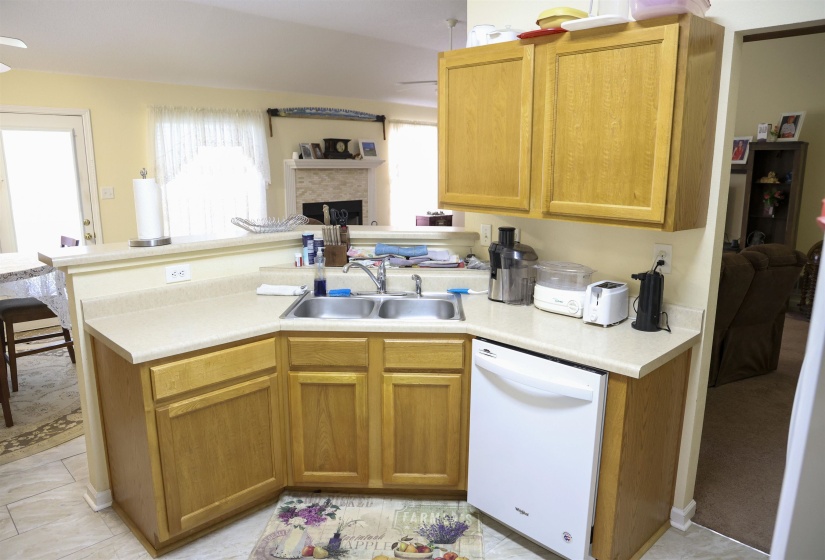 Functional kitchen featuring wood-finish cabinetry, a double basin stainless steel sink, and light-toned countertops