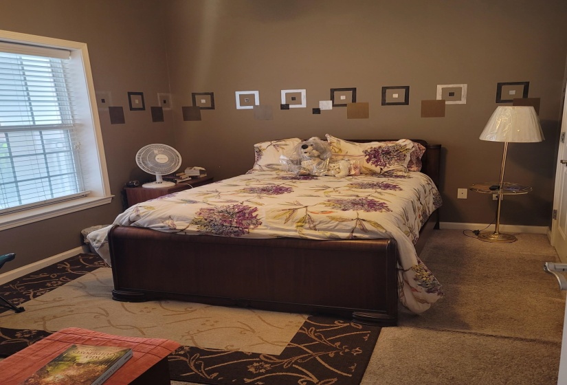 Spacious room featuring a large window with blinds, wall-to-wall carpeting, and a decorative wall accent