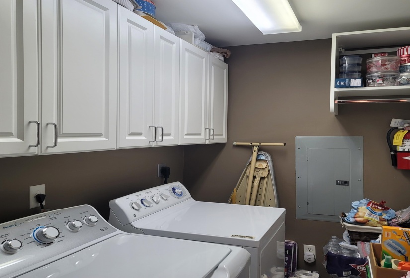 White shaker-style cabinetry with brushed nickel hardware, expansive wall-mounted shelving with hanging rod, and neutral wall color
