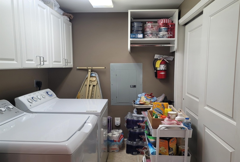 Utility area featuring upper cabinetry with brushed nickel hardware, a flush-mounted ceiling light fixture, and a sliding panel door