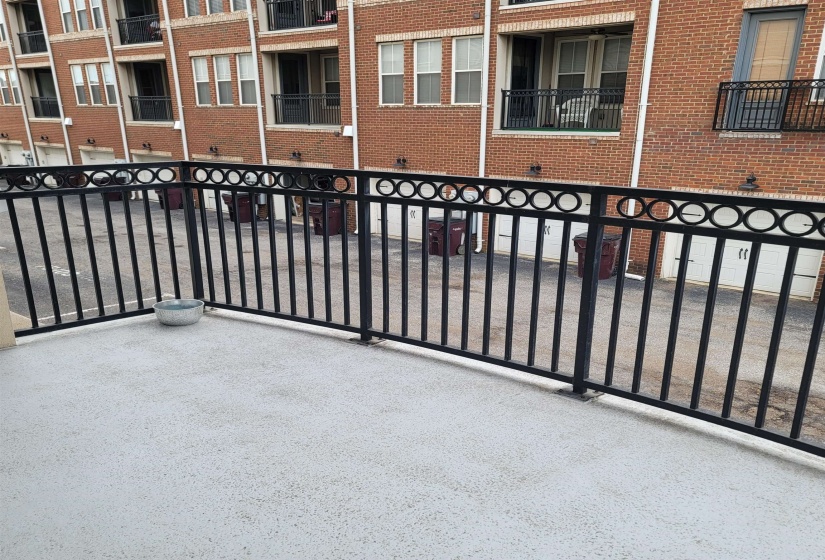 Balcony with decorative black metal railing and light-colored concrete flooring