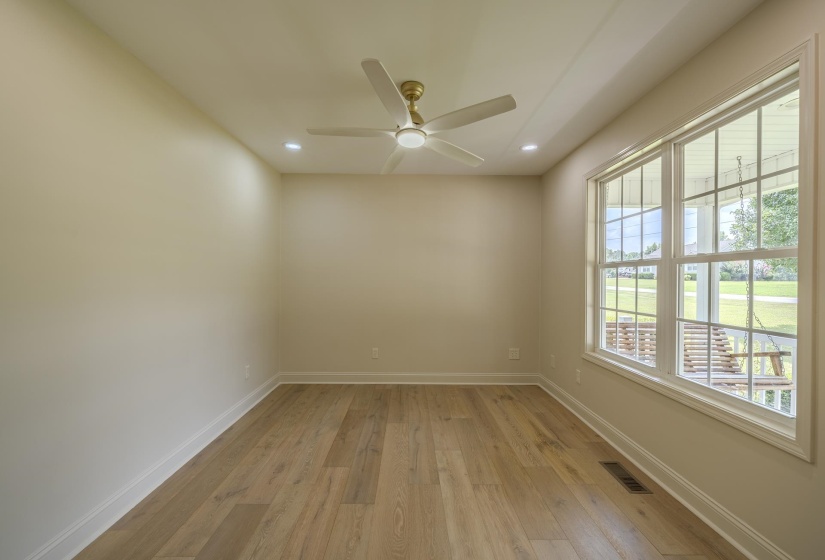Bright room with wood-finish flooring, featuring a large multi-pane window, recessed lighting, and a ceiling fan