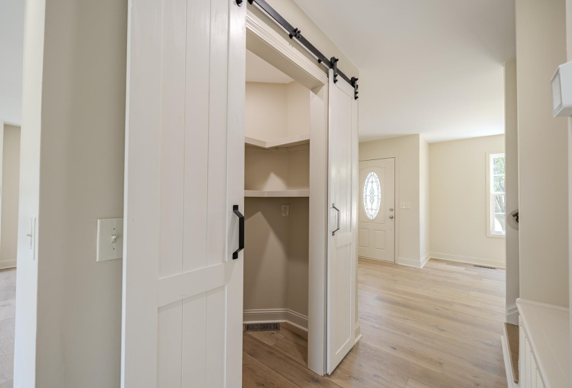 White barn door pantry with black hardware, featuring interior shelving