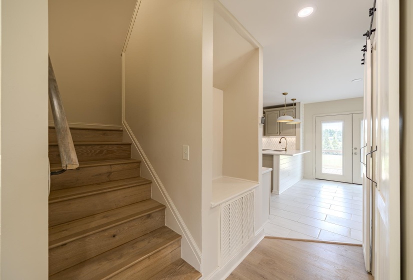 Wood-finish flooring extending into a light-toned staircase with a wood handrail