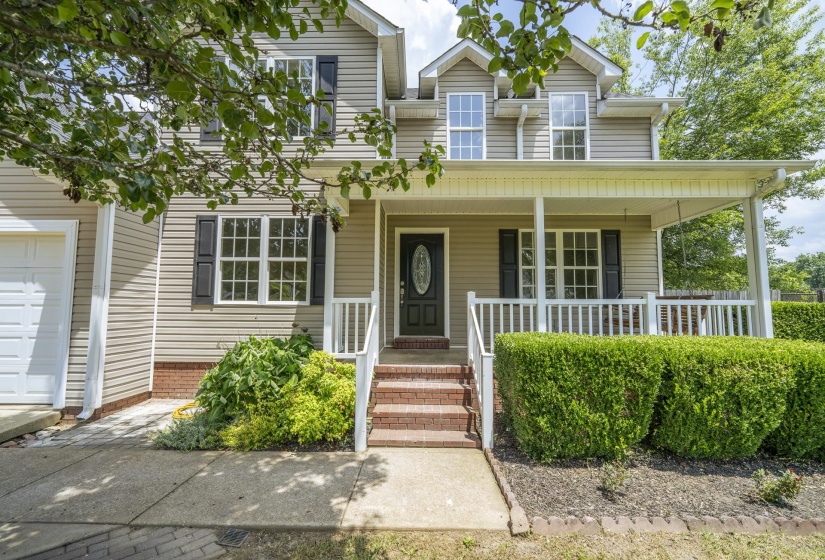 Two-story residence featuring light-colored siding, a covered front porch with white railing, and a brick-accented foundation