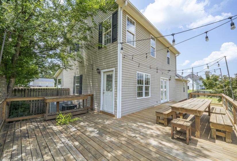 Spacious wood-finish deck featuring string lighting, built-in bench seating, and wood-panel siding