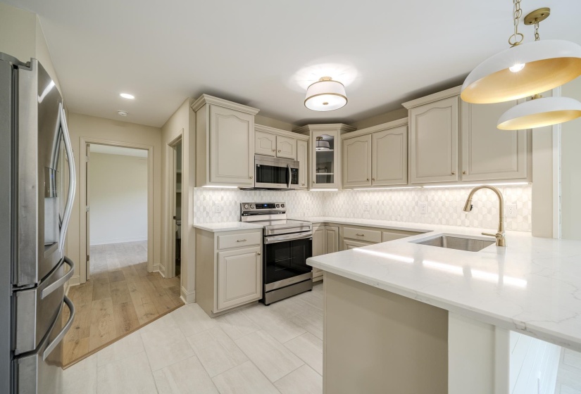 Contemporary kitchen featuring light cabinetry, stainless steel appliances, and a central island with a built-in sink