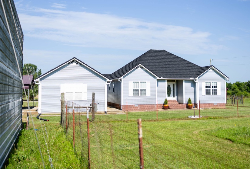 Single-story residence featuring light blue siding, a dark shingle roof, and a partial brick foundation