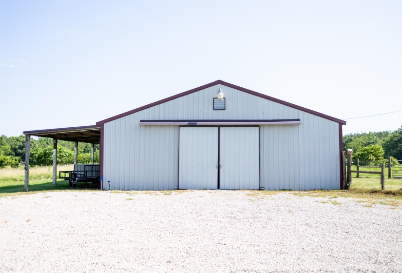 Metal barn structure with a pitched roof, light-colored siding, and dark trim
