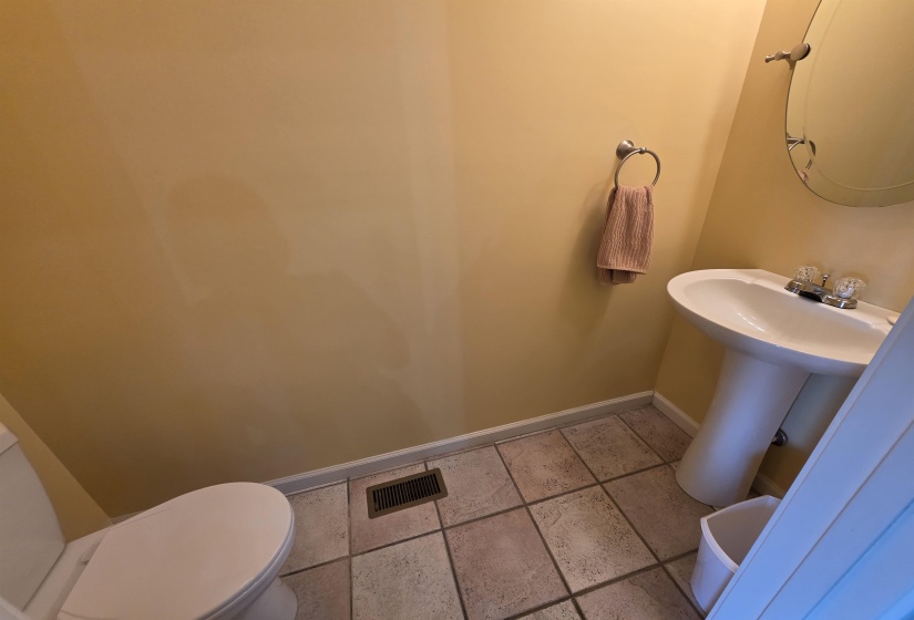Pedestal sink with chrome fixtures, oval mirror, and tile flooring