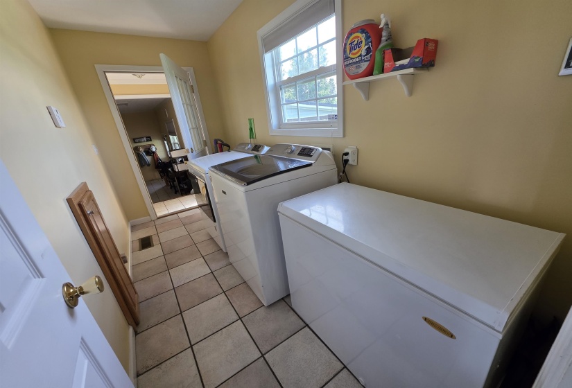 Utility area featuring ceramic tile flooring, a window with natural light, and a wall-mounted shelving unit