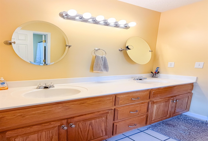 Dual vanity featuring light wood cabinetry, white countertops, and integrated sinks