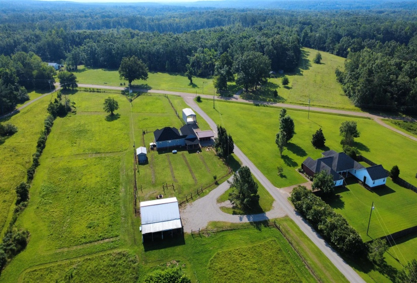 Expansive rural property featuring two distinct residences, multiple outbuildings, and a surrounding wooded landscape