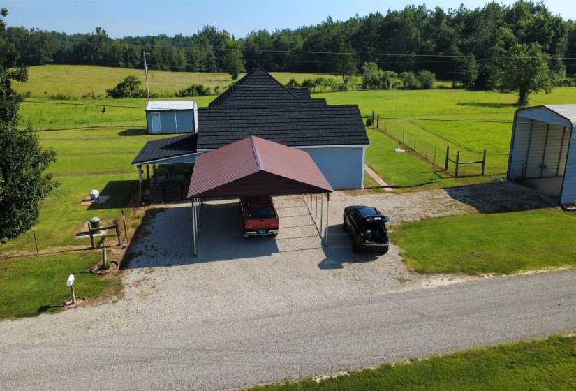 Ranch-style residence featuring a dark shingle roof, light blue siding, and an attached metal carport