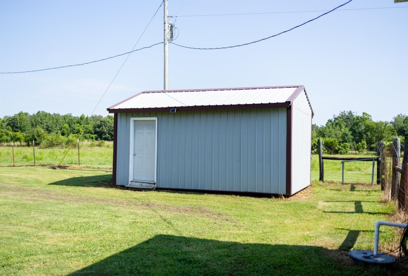 Storage shed featuring light blue metal siding, a white metal roof, and a brown trim