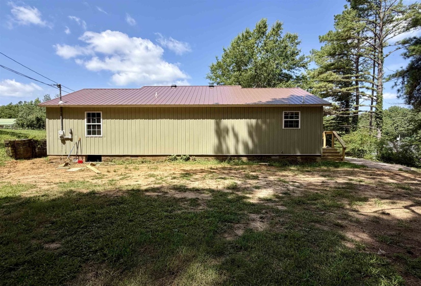 Light green vertical siding with a contrasting deep red metal roof