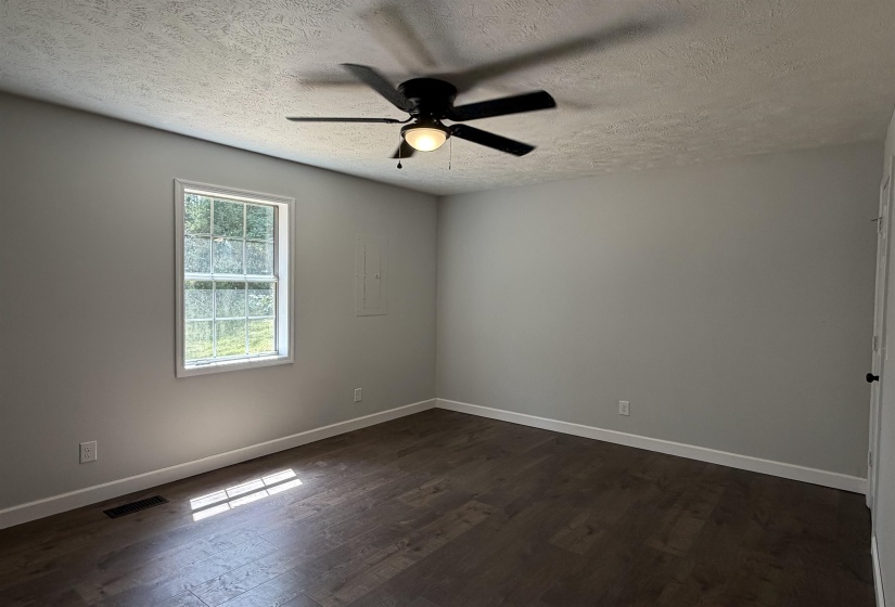 Room featuring wood-finish flooring, a window with exterior views, and a ceiling fan with integrated lighting