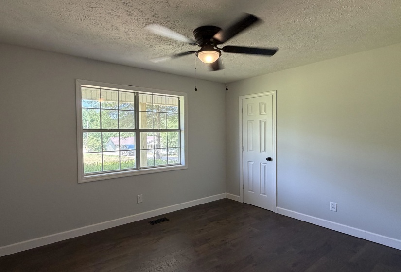 Spacious room featuring wood-finish flooring, light gray walls, and white baseboards