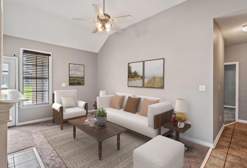 Spacious living area featuring vaulted ceilings, a ceiling fan, and carpet flooring