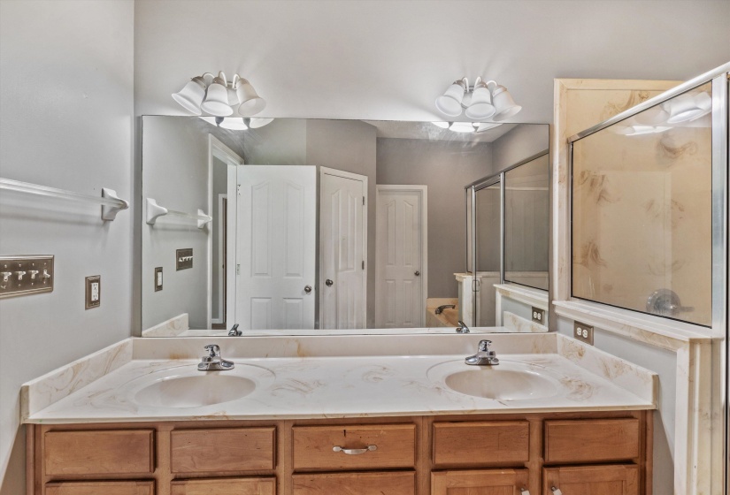 Double vanity with integrated sinks, light-toned countertop, and wood-finish cabinetry