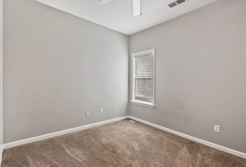 Neutral-toned room with plush carpet flooring, a single window with blinds, white baseboards, and a ceiling fan