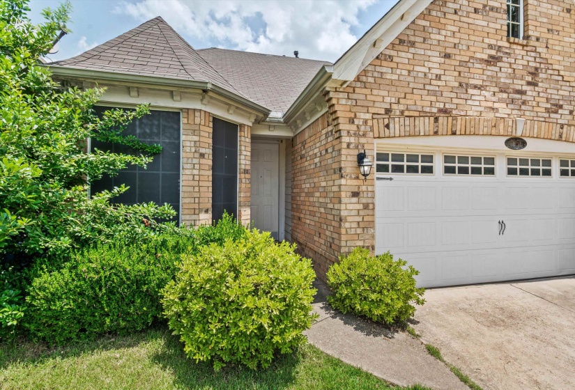 Brick exterior featuring a two-car garage with paneling and upper window inserts