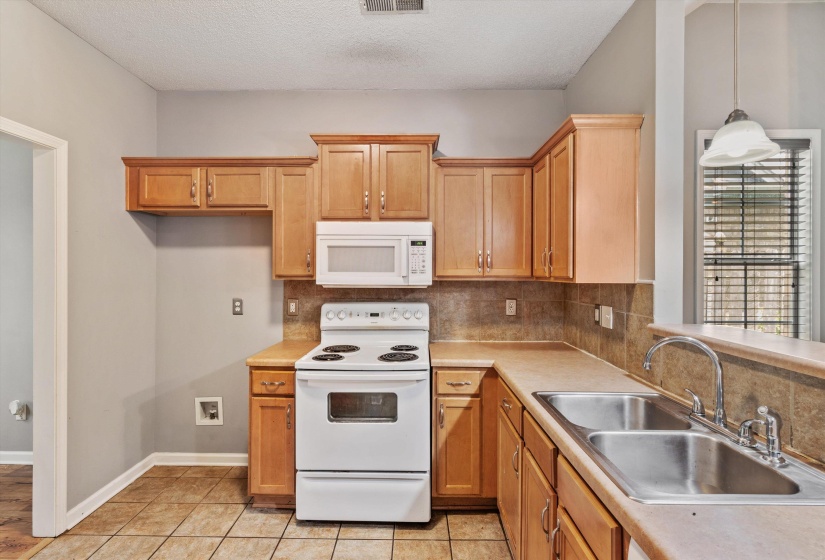 Kitchen featuring wood cabinetry, a white electric range, a built-in microwave, and a double basin stainless steel sink