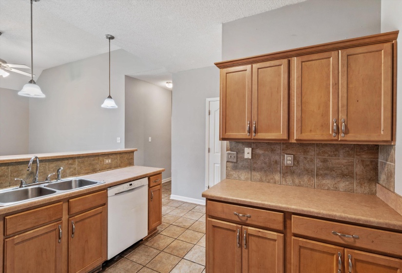 Kitchen featuring wood-finish cabinetry, a double basin stainless steel sink, and a white dishwasher