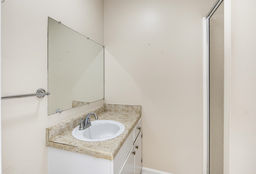 Bathroom vanity with white cabinetry, an integrated sink, and a speckled countertop