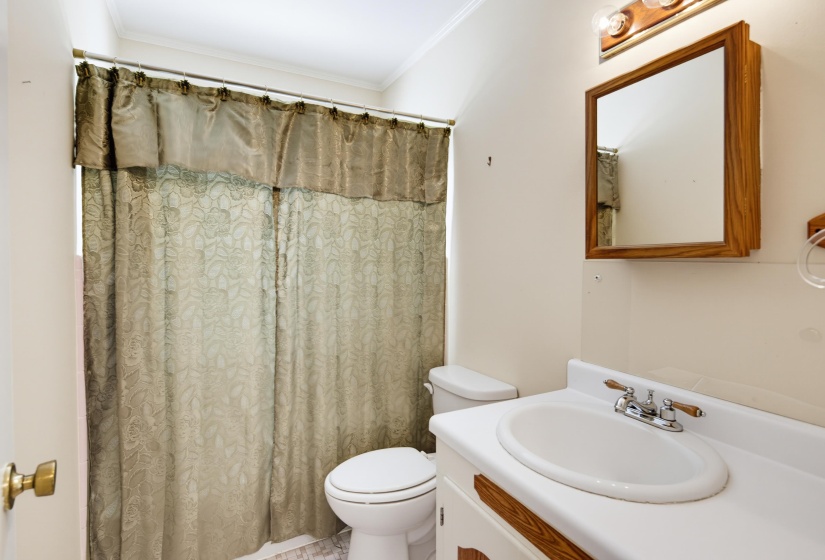Bathroom featuring a single vanity with an integrated sink, a wood-framed mirror, and an overhead vanity light fixture