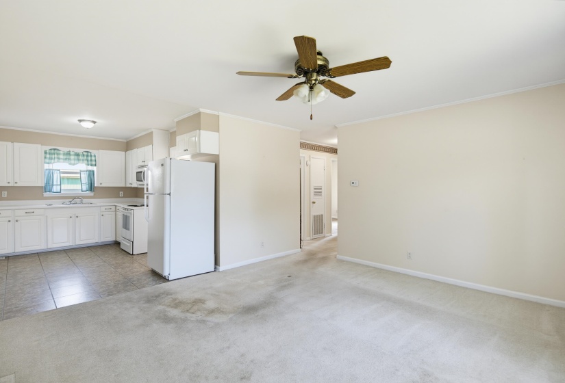 Kitchen and living area featuring white cabinetry, white appliances, light-toned countertop, and tile flooring
