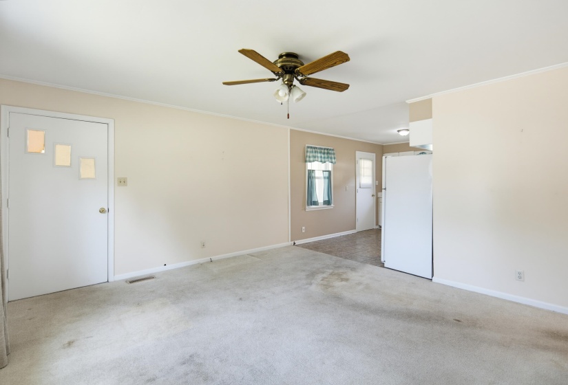 Open-concept living space featuring neutral walls, ceiling fan, and carpeted flooring
