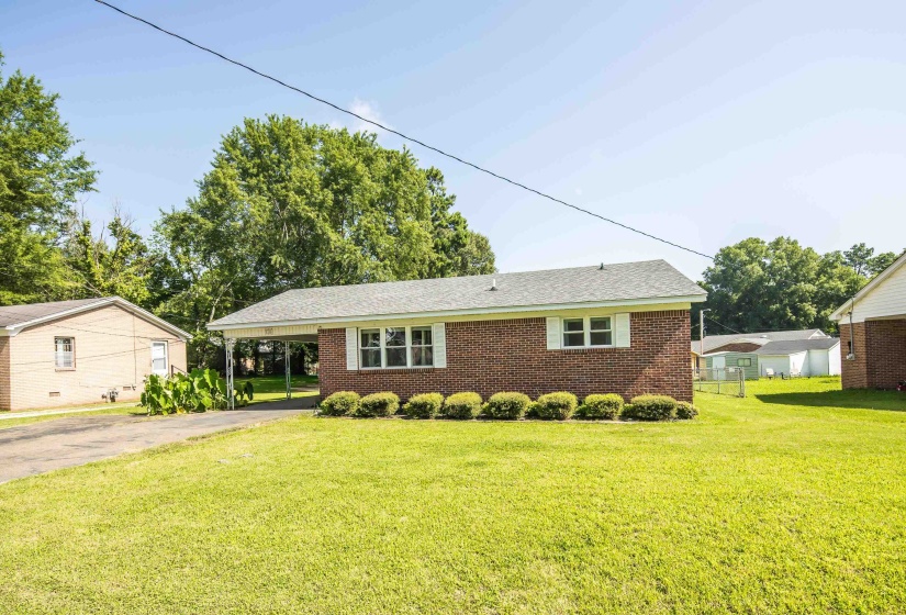 Brick exterior ranch-style residence featuring a carport and established landscaping