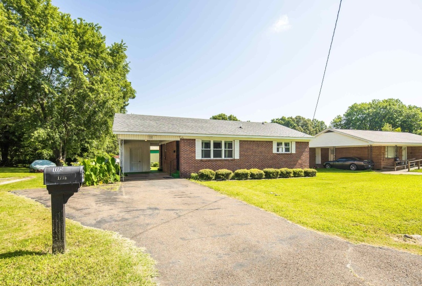Brick exterior residence featuring a carport and asphalt driveway