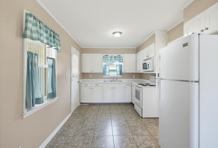 Kitchen featuring white cabinetry, solid surface countertops, a full suite of white appliances, and tiled flooring