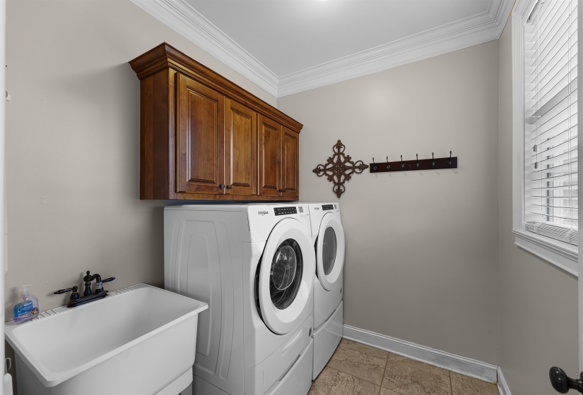 Laundry room featuring washer and dryer, cabinet space, and ornamental molding