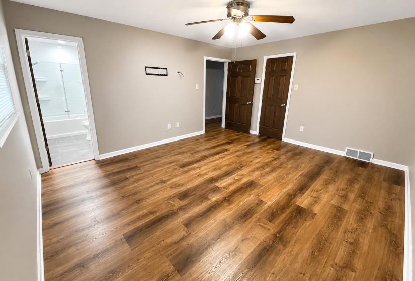 Spacious room featuring wood-finish flooring, neutral-toned walls, and a ceiling fan with integrated lighting
