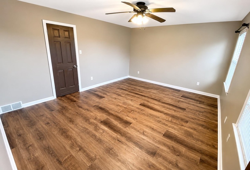 Spacious room featuring wood-finish flooring, neutral-toned walls, and white baseboards