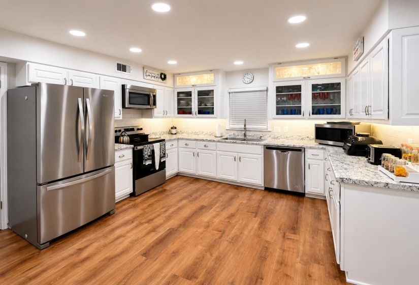 Kitchen featuring wood-finish flooring, recessed lighting, stainless steel appliances, white cabinetry, and light-toned countertops