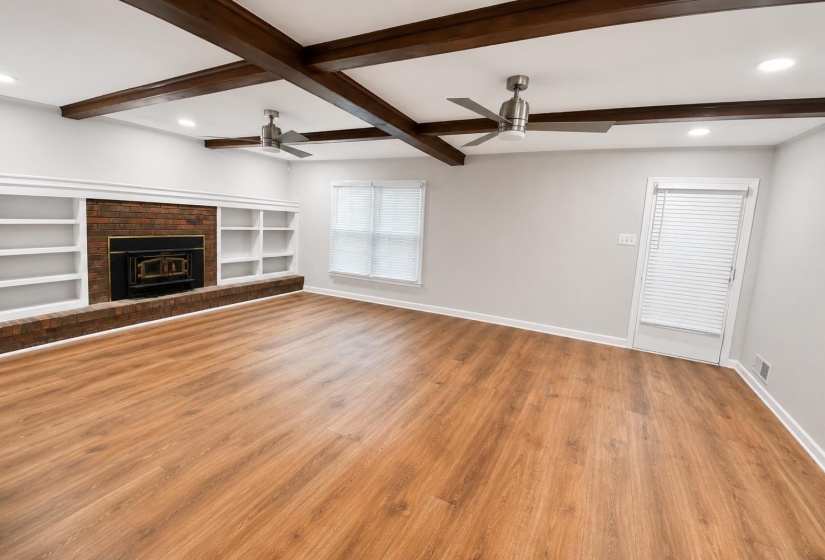 Spacious room with wood-finish flooring and exposed ceiling beams