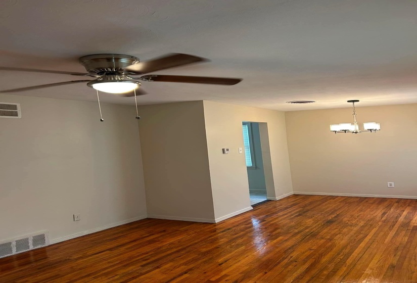 Hardwood flooring throughout featuring a ceiling fan with integrated lighting, a contemporary chandelier, baseboard molding, and neutral wall tones