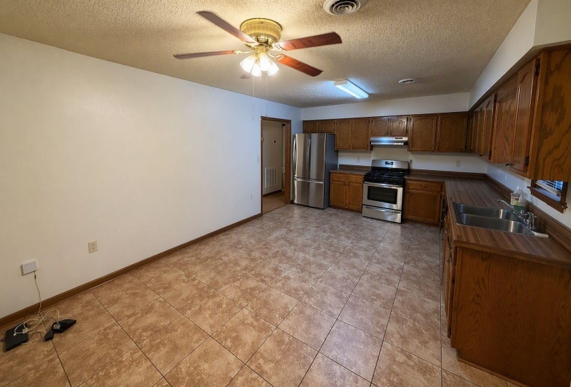 Kitchen featuring a ceiling fan, recessed lighting, wood-finish cabinetry, stainless steel appliances, and a double basin sink