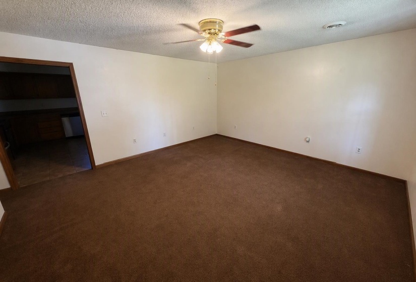 Spacious room featuring brown carpet flooring, neutral painted walls, and a ceiling fan with integrated lighting