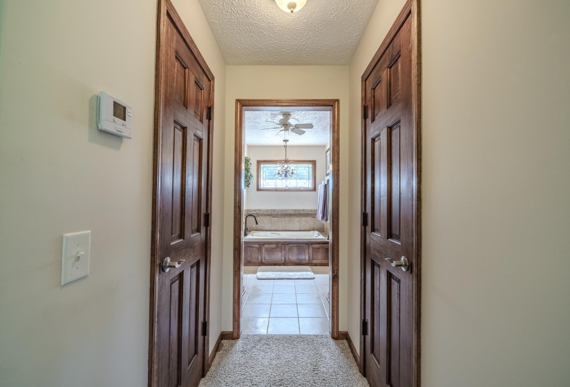 Hallway featuring two panel doors with wood-finish trim, a wall-mounted thermostat, and a light switch