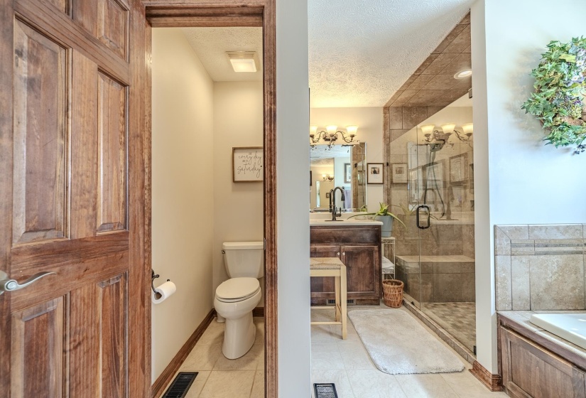 Spacious bathroom featuring a glass-enclosed shower with a built-in bench, dark wood vanity with a vessel sink, and an adjacent water closet