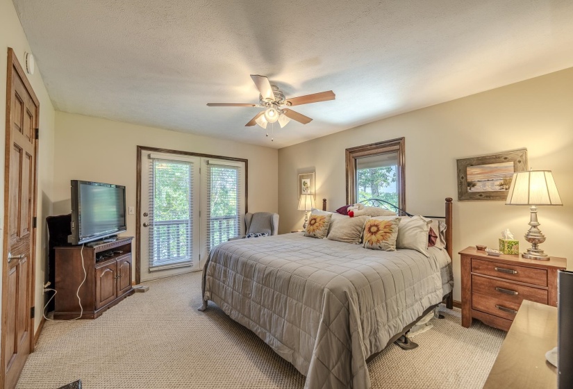Carpeted room featuring a ceiling fan with light fixture, double doors, and a window with wood trim