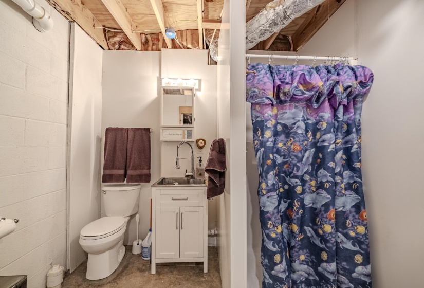 Compact bathroom featuring a white toilet, a vanity with cabinet storage, and a sink with a gooseneck faucet